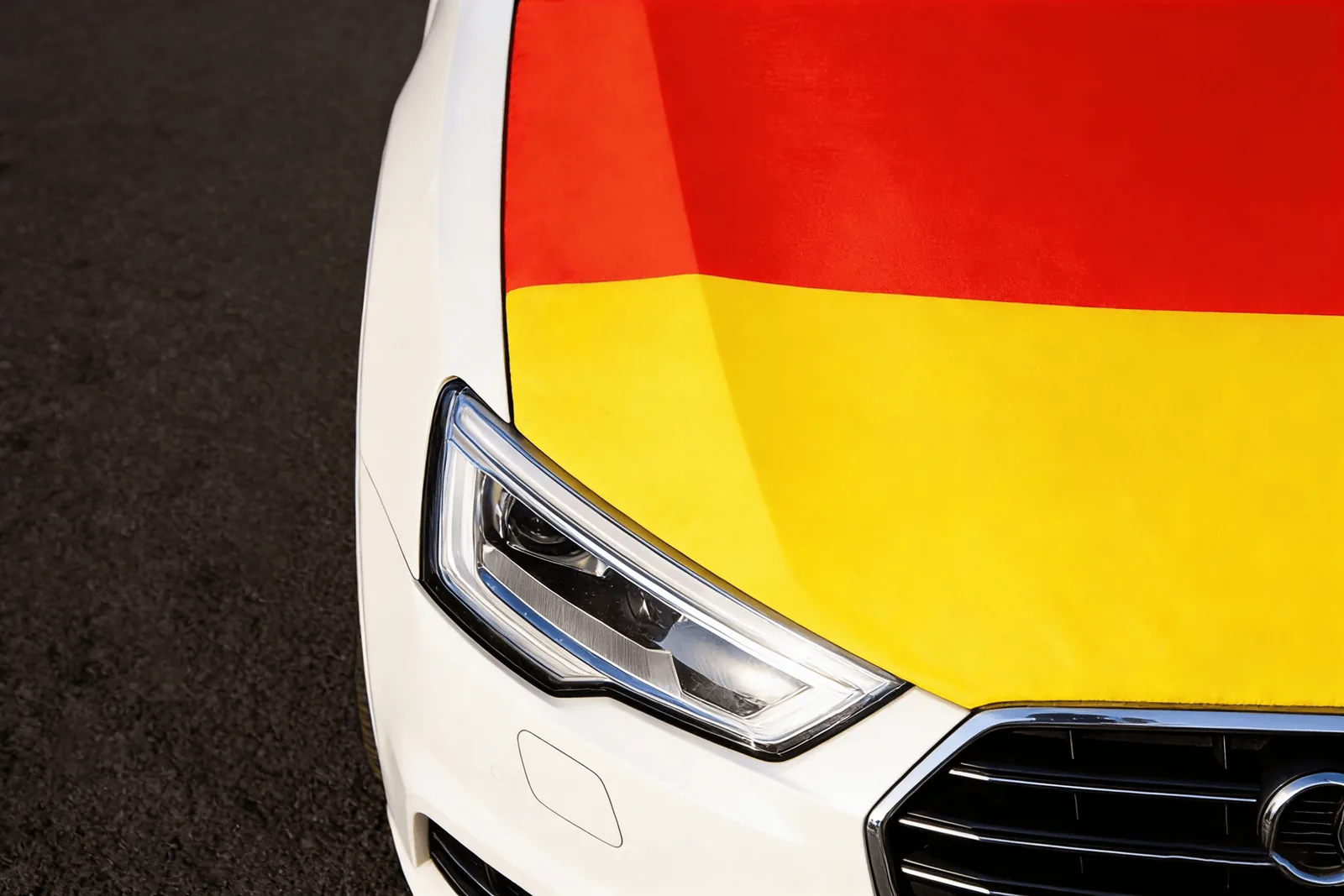 Close-up of a Germany-colored car hood cover fitted on a white car