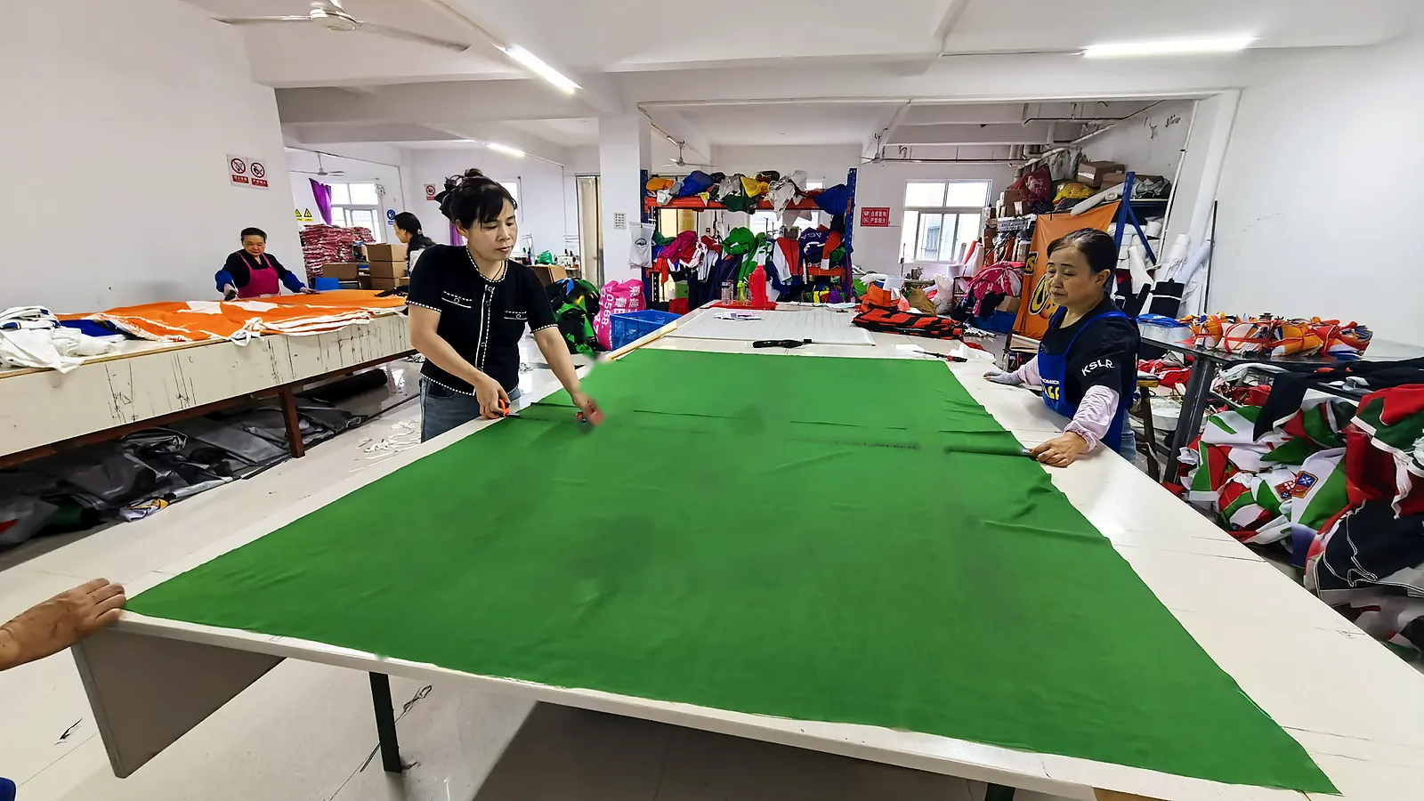 Quality inspection of a large custom flag on the inspection table at Senior Flags