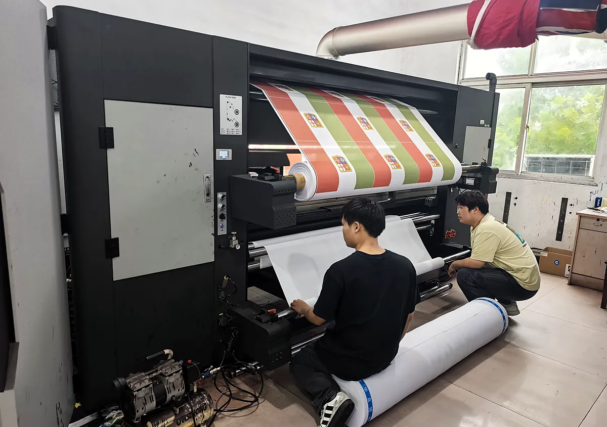 Operators running a large-format digital printer for custom flags at Senior Flags