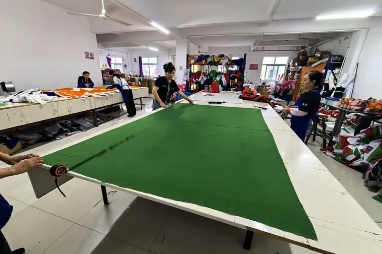 Workers measuring a finished custom flag with a tape measure during final inspection
