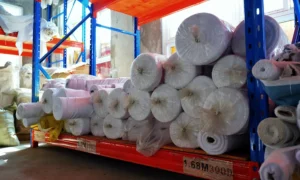 Rolls of 300D polyester flag fabric on warehouse racks at Senior Flags