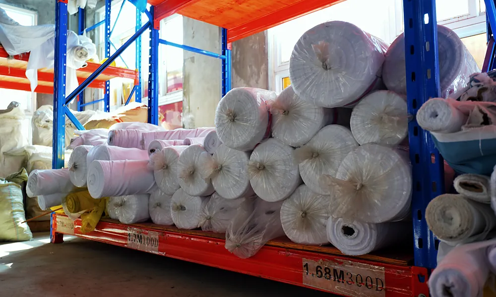 Rolls of 300D polyester flag fabric on warehouse racks at Senior Flags