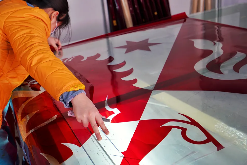 Worker checking a screen printing film on a light table during flag production