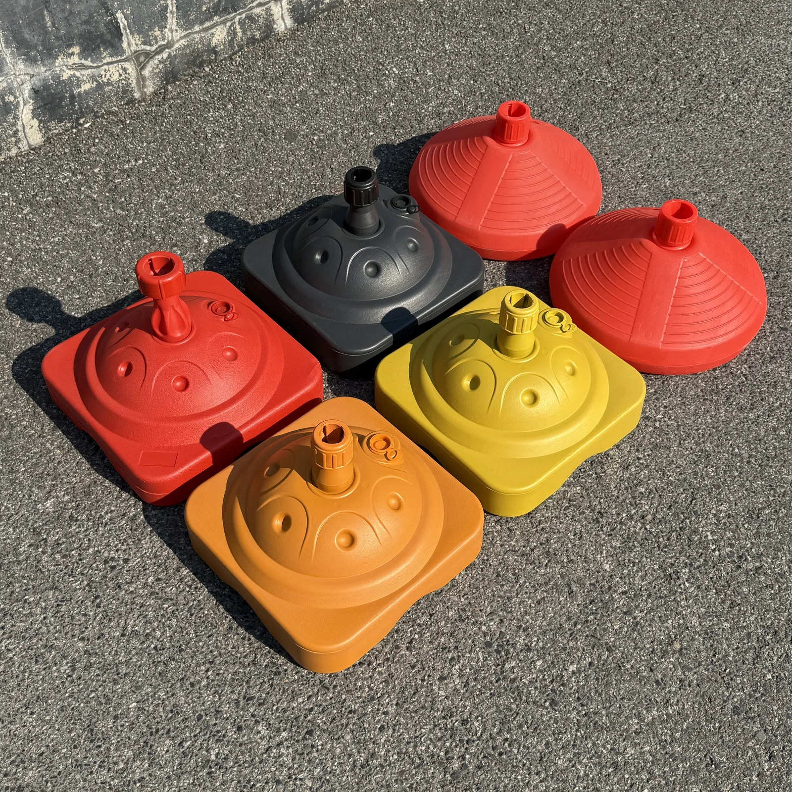 Plastic water-fill umbrella bases in red, black, orange and yellow